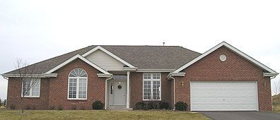 Red brick ranch-style house with white trim, a garage, and a cloudy sky.