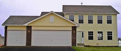 Two-story house with three-car garage, yellow siding, brick accents, and gray roof.