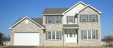 Two-story brick house with grey shutters, garage, and a clear blue sky.