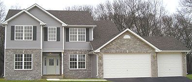 Two-story house with gray siding, brick accents, and three-car garage with white doors.