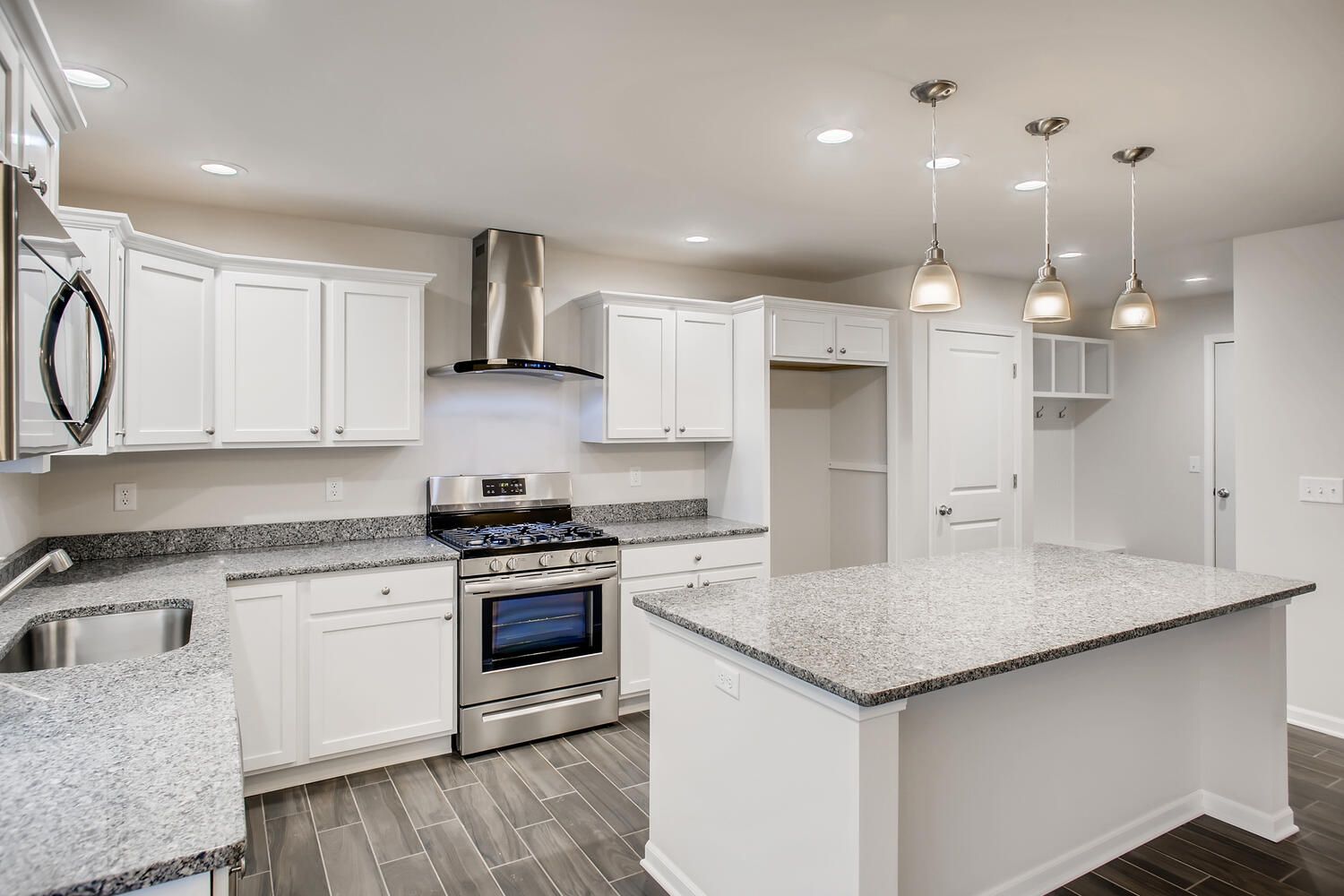 White kitchen with stainless steel appliances, granite countertops, and a large island.