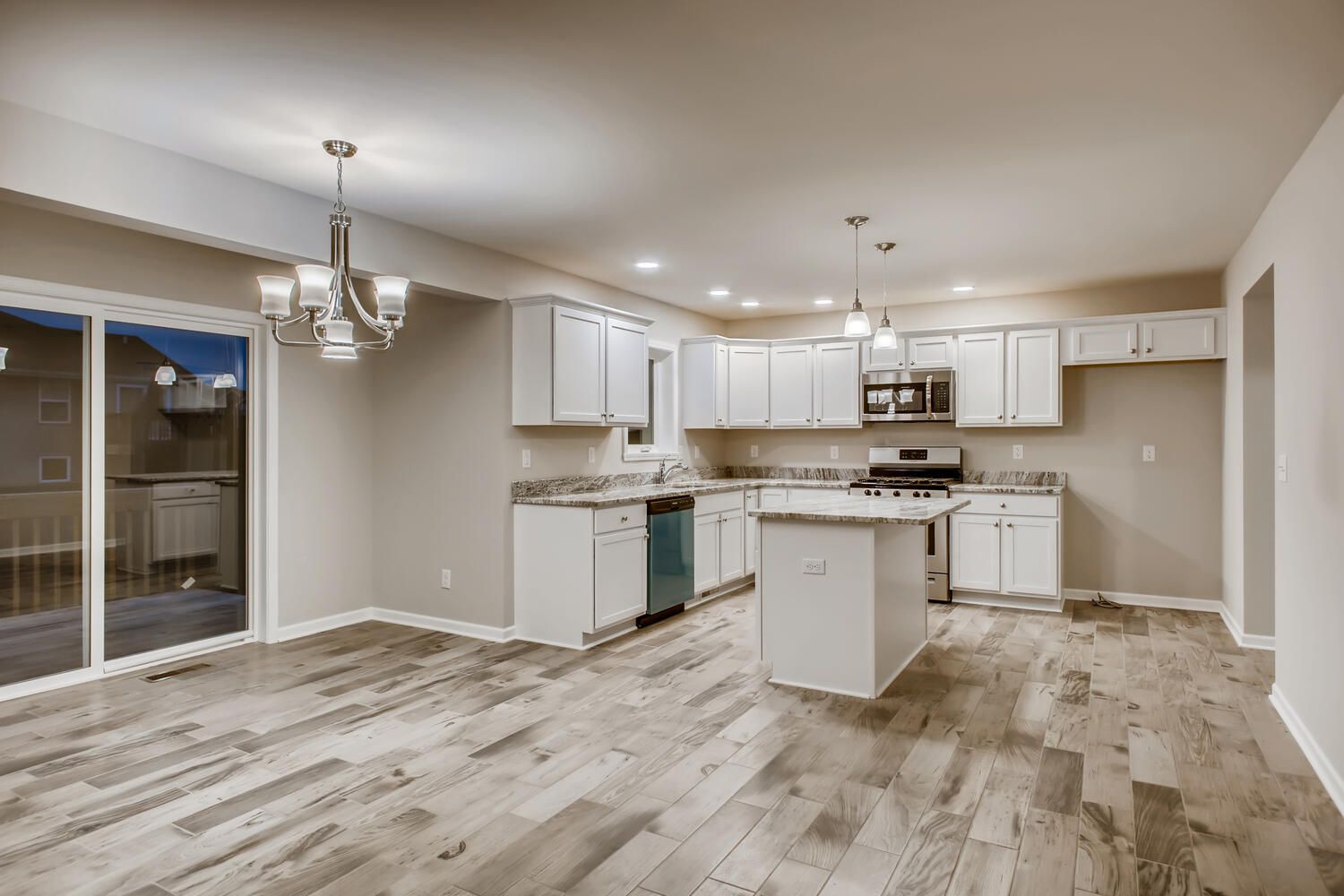 White kitchen with island, stainless steel appliances, and light wood floors.