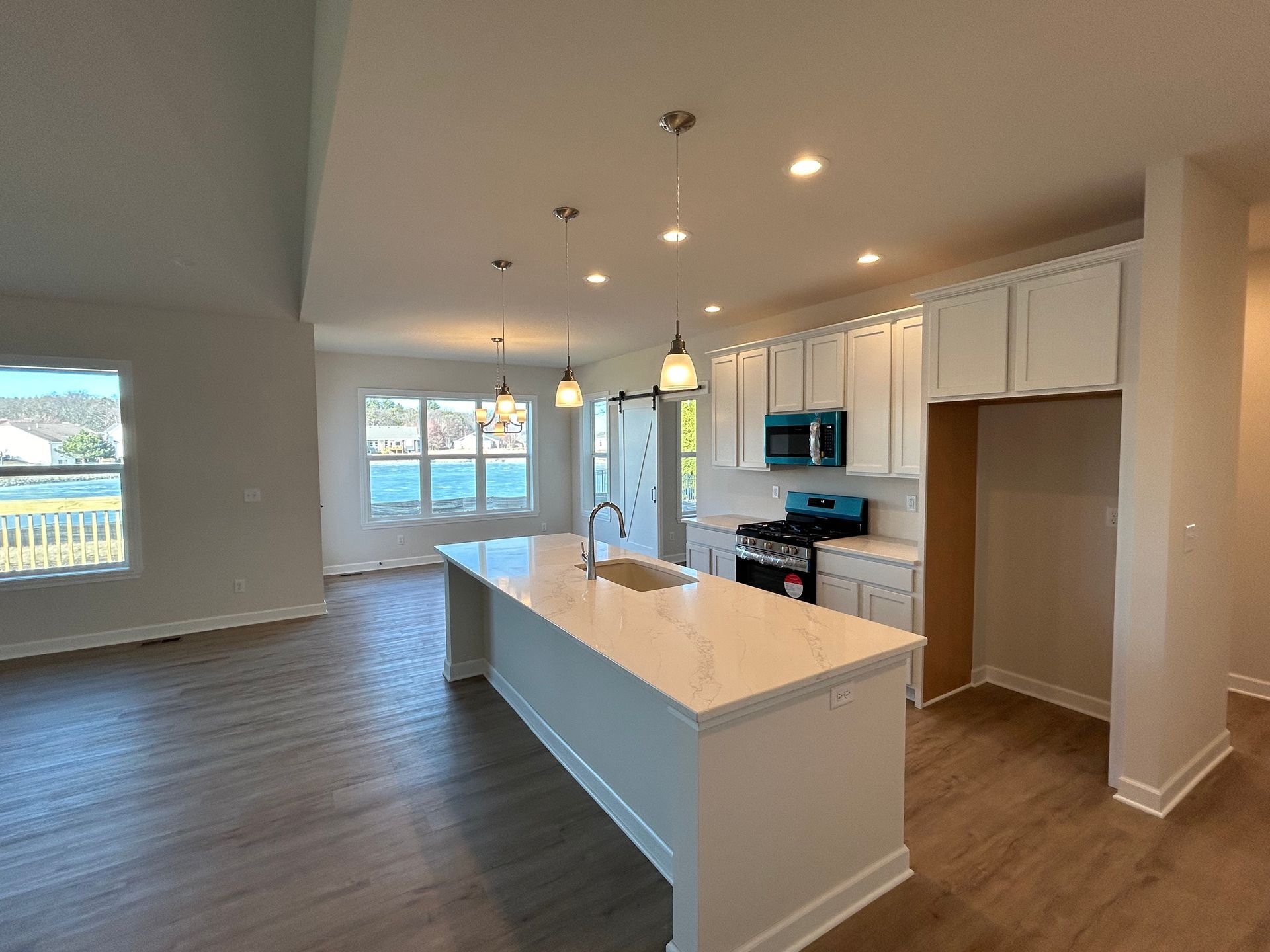 Modern kitchen with white cabinets, blue microwave, and a large island.