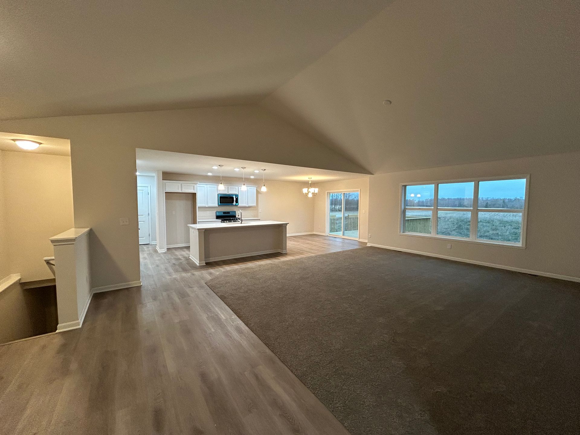 Interior of a home featuring an open floor plan with a kitchen, living room, and staircase.