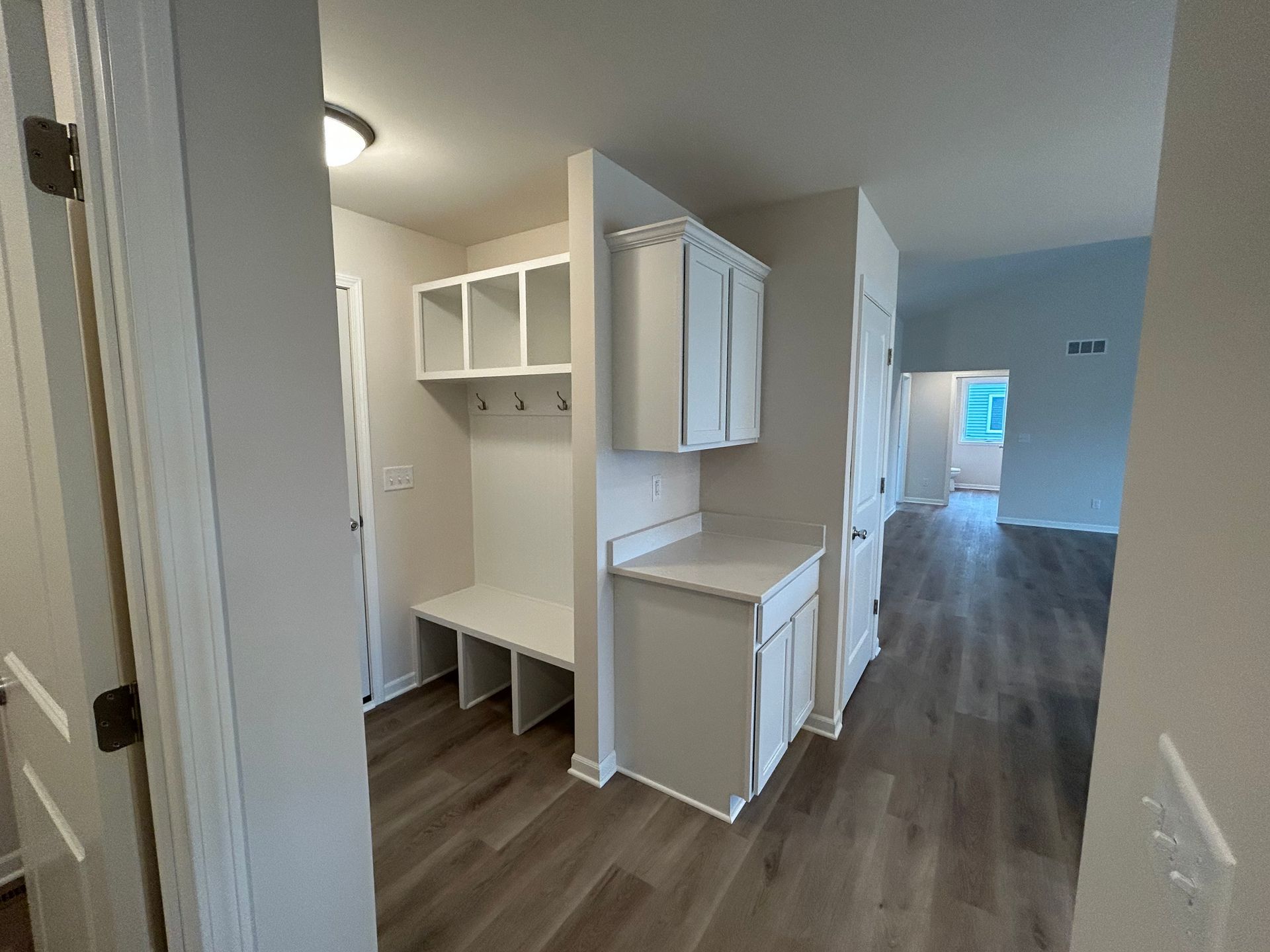 Mudroom with built-in bench, cubbies, and cabinets. Light gray and white with wood flooring.