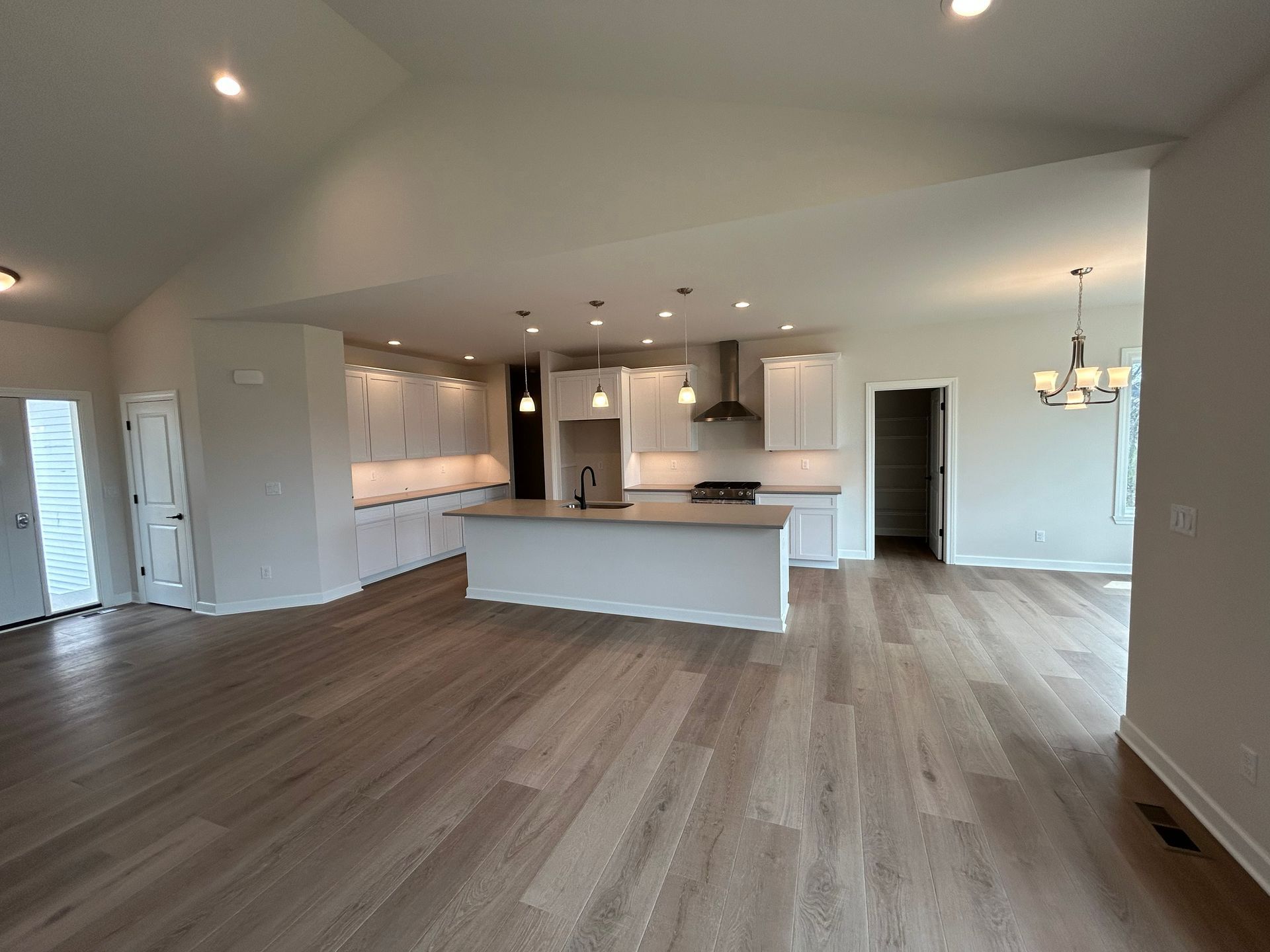 Open-concept kitchen and living area with white cabinets, island, and light wood flooring.