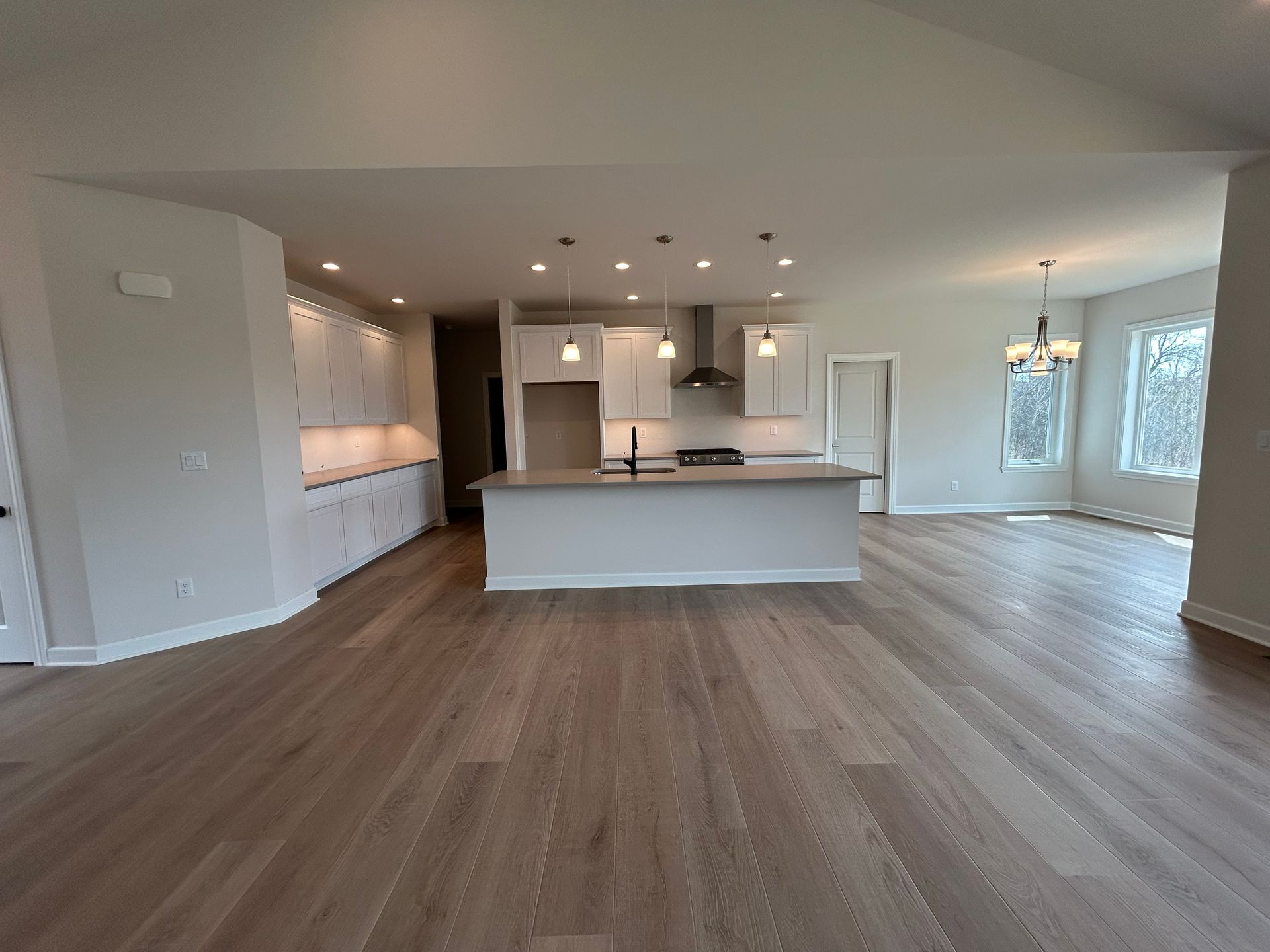 Open-concept kitchen and dining area with light wood floors, white cabinets, and a large island.