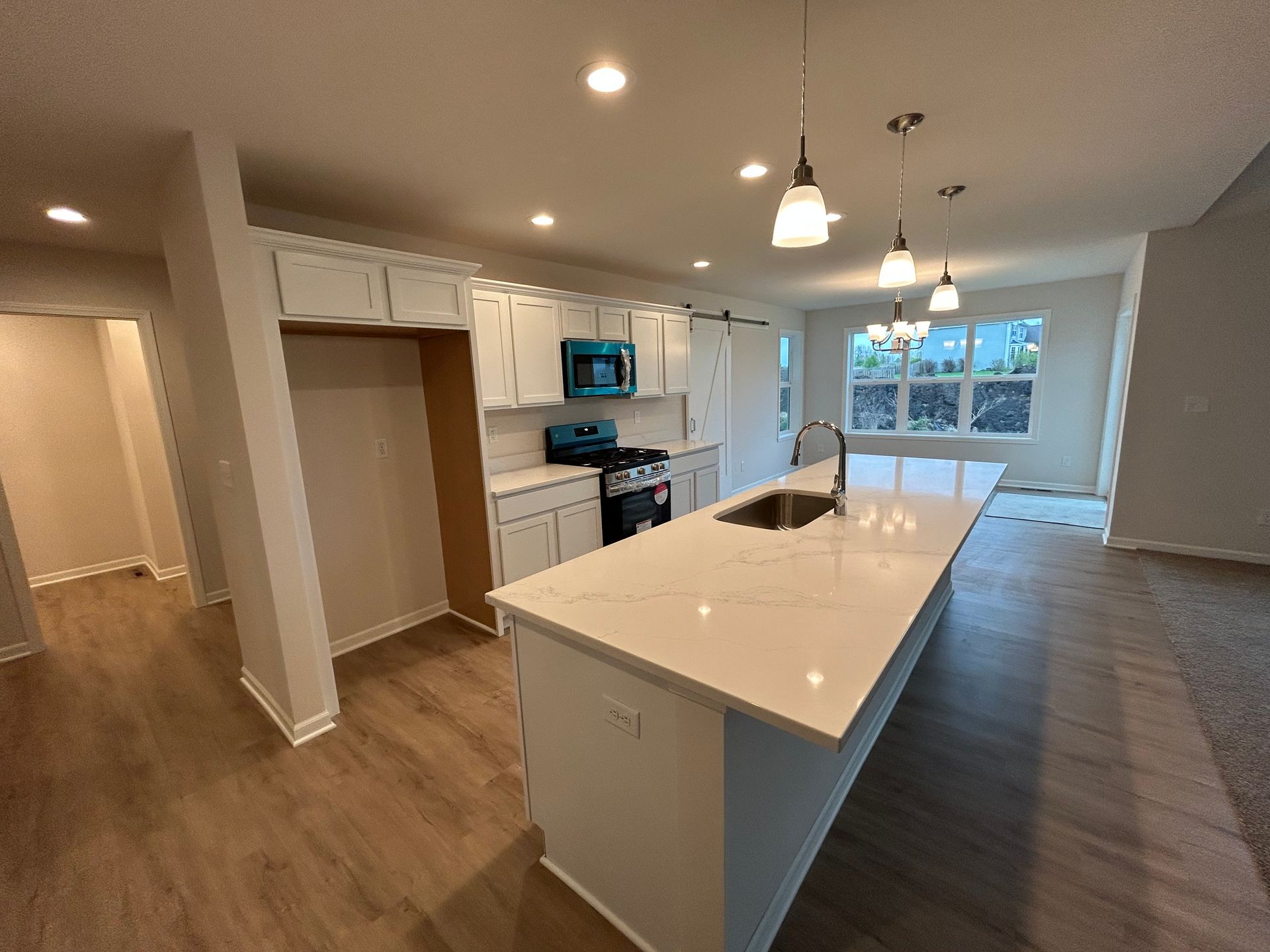 Modern kitchen with white cabinets, island, stainless steel appliances, and light wood floors.