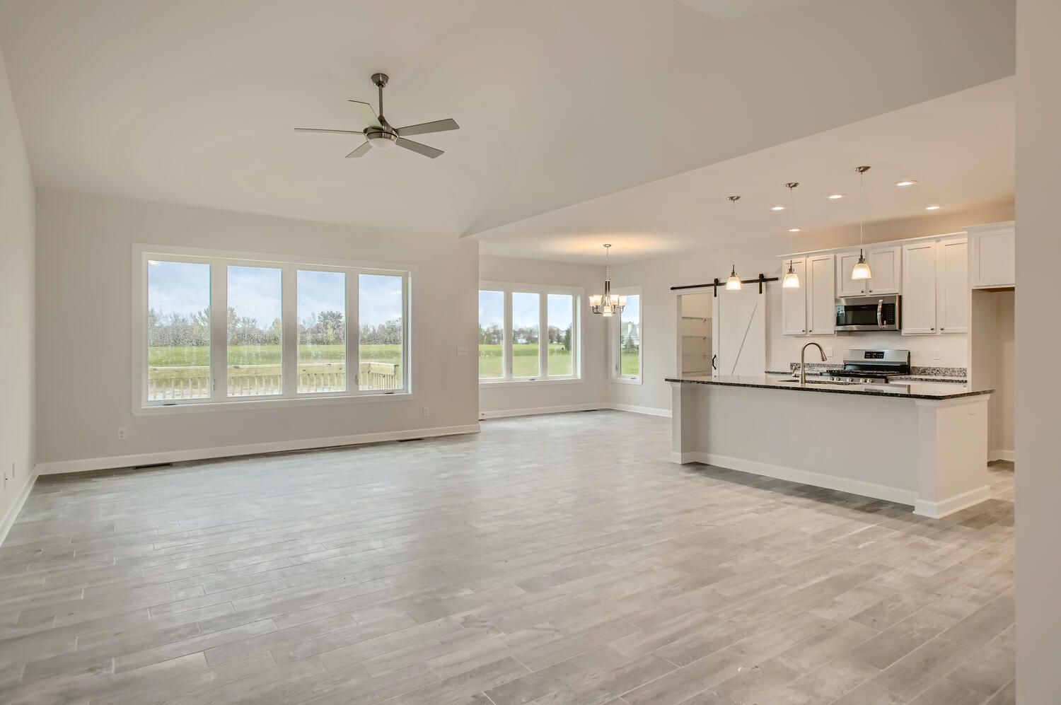 Open-concept living space with kitchen, windows, and light gray flooring.