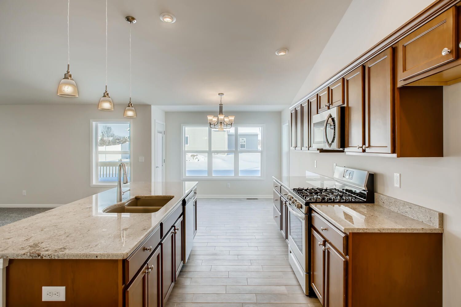 Spacious kitchen with granite counters, wooden cabinets, stainless steel appliances, and an island.