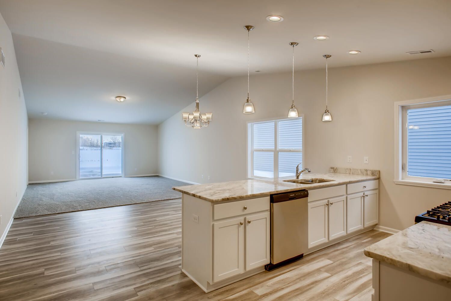 Open-concept kitchen and living room with white cabinets, granite countertops, and sliding glass door.