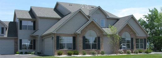 A two-story house with a gray roof and siding, a brick facade, and a green lawn.