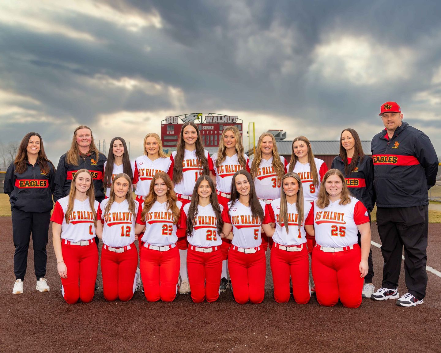 A group of girls are posing for the girls' softball team photo.