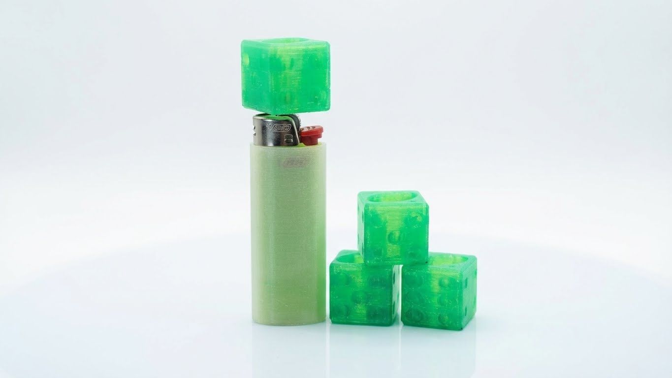 Green lighter beside a green textured rectangular object on a plain white background