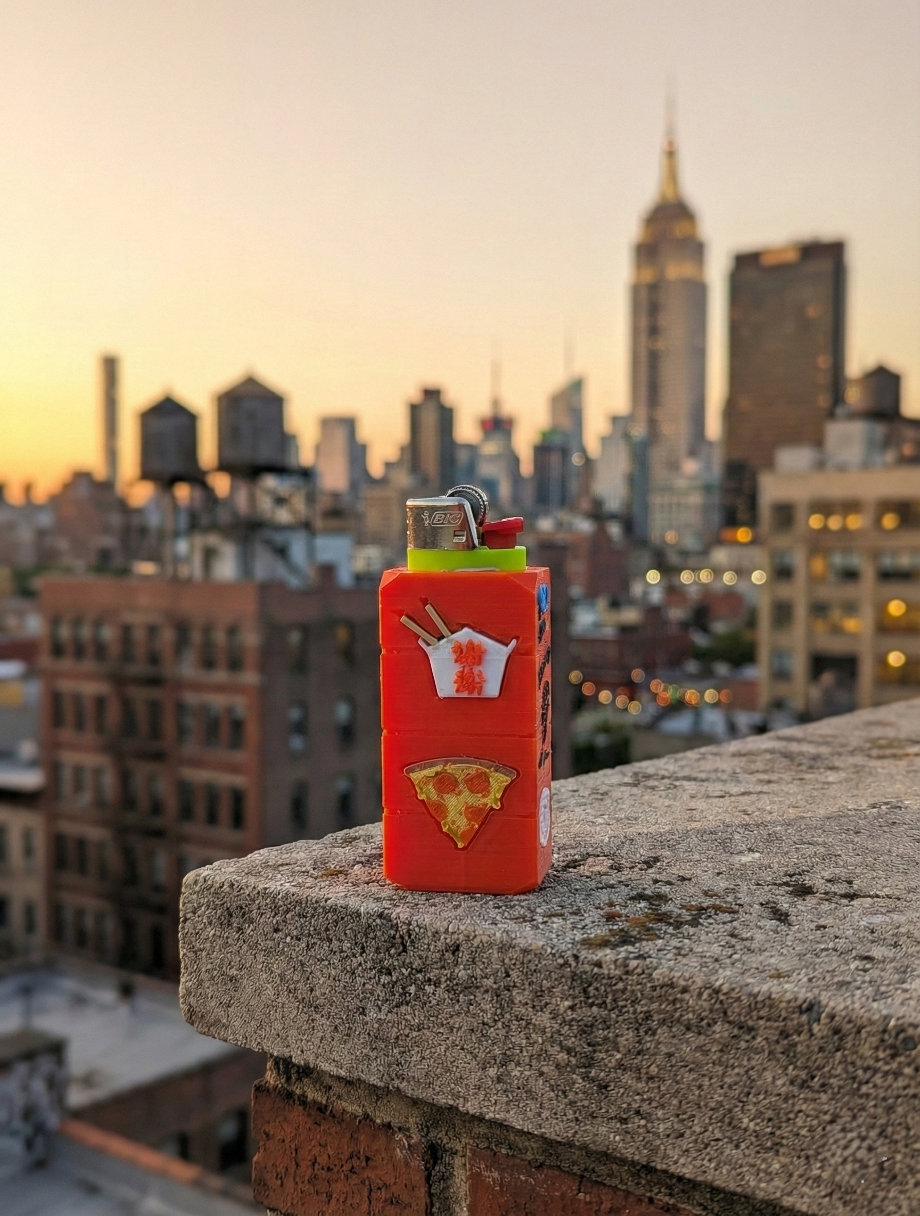 Red bottle on concrete with tiny shoes and hats arranged around it against a brick wall.
