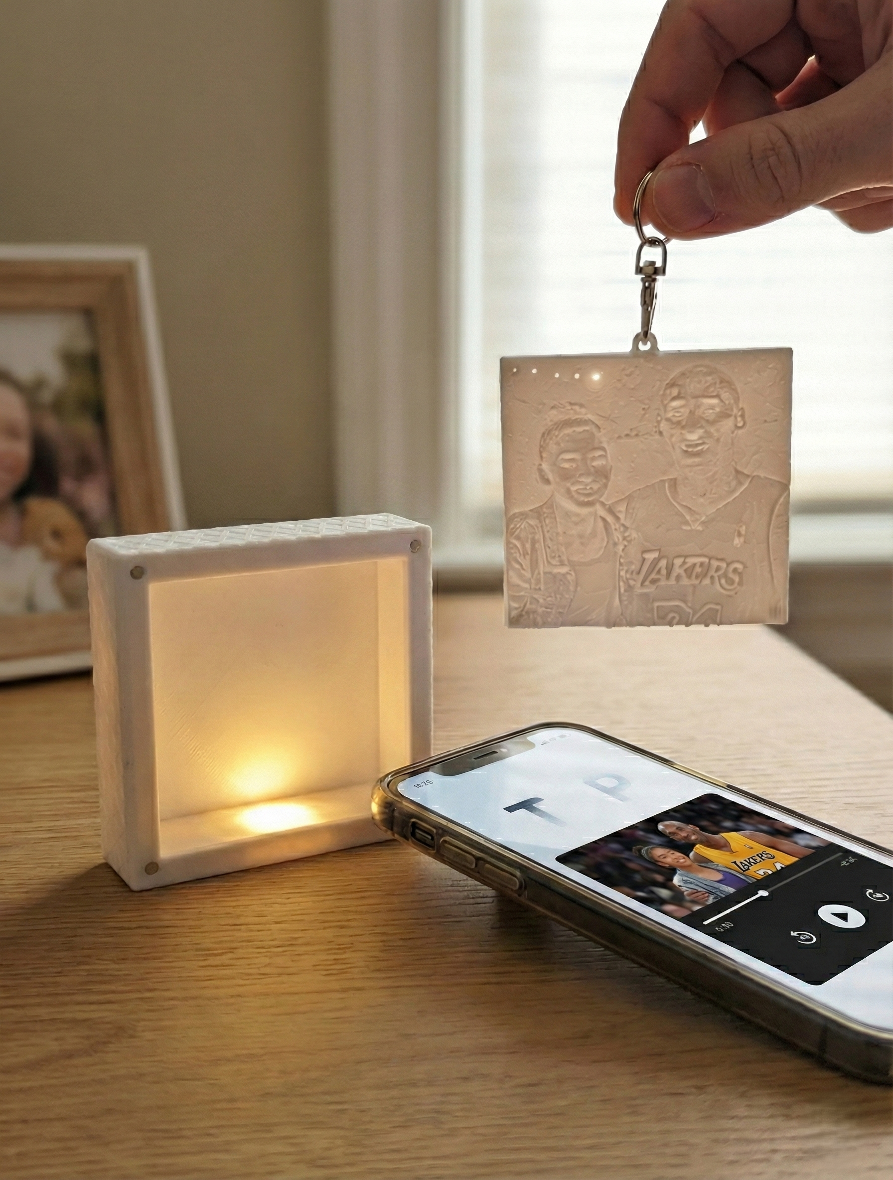 Keychain with etched photo charm hanging from a brown handbag on a sunny sidewalk