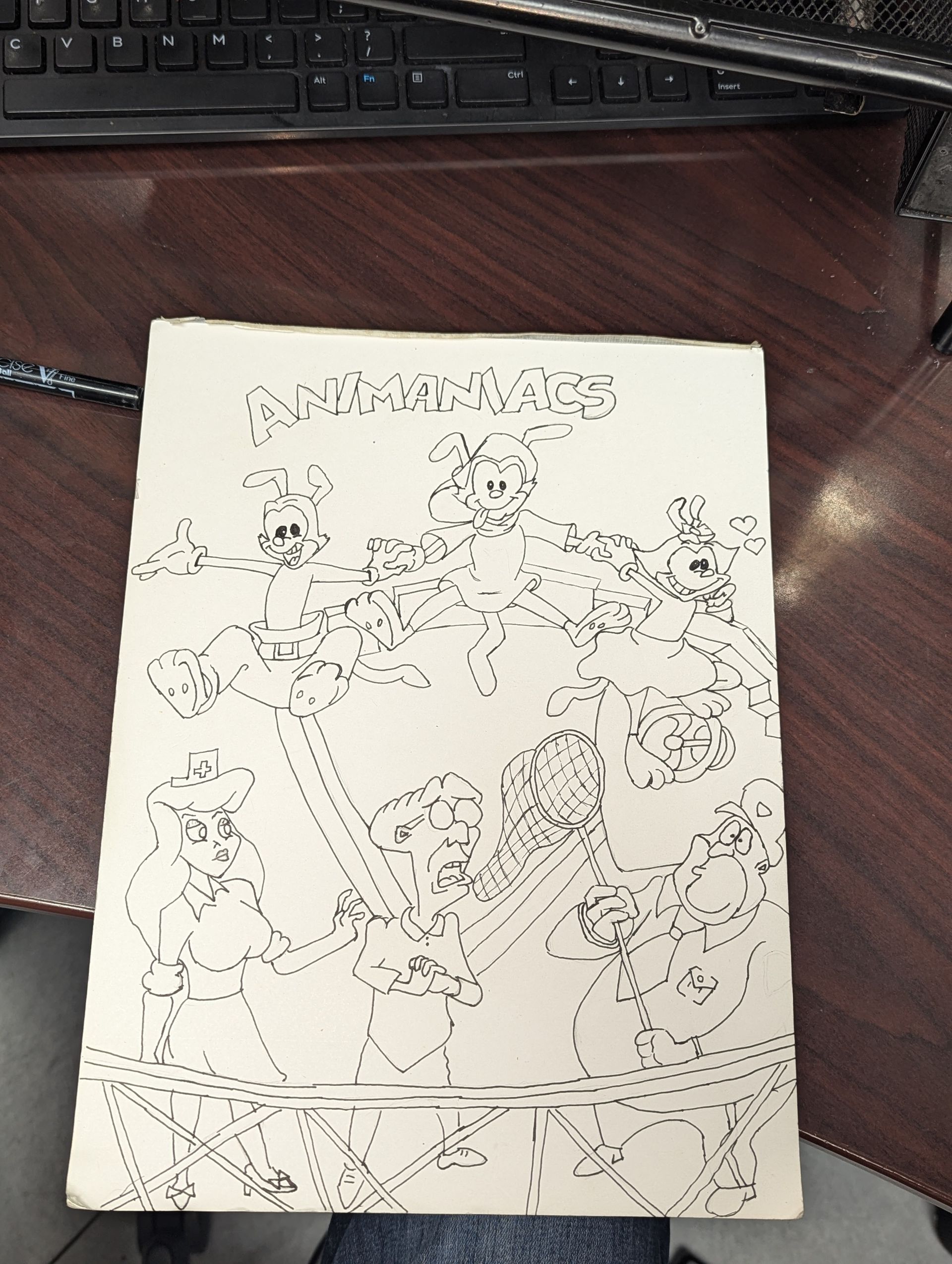 Partially completed line-art coloring page on a desk, with scattered doodles and a central character sketch
