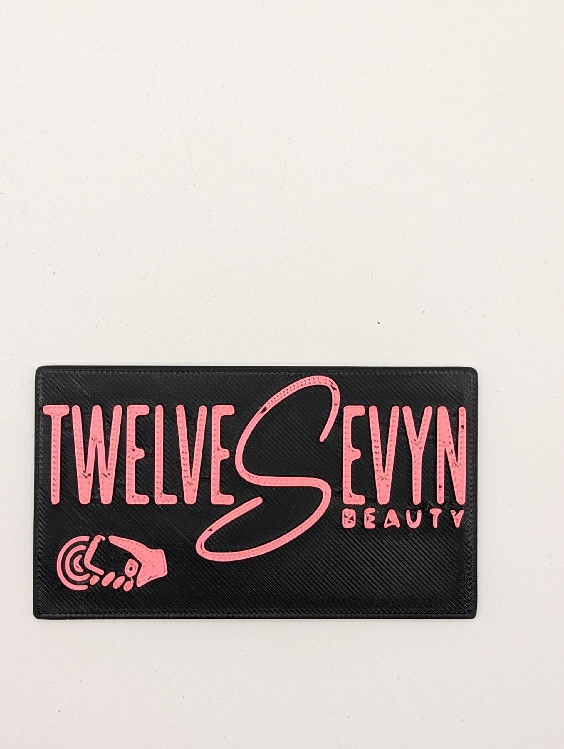 Hand holding smartphone beside hair tools on a vanity with a salon card and product bottles
