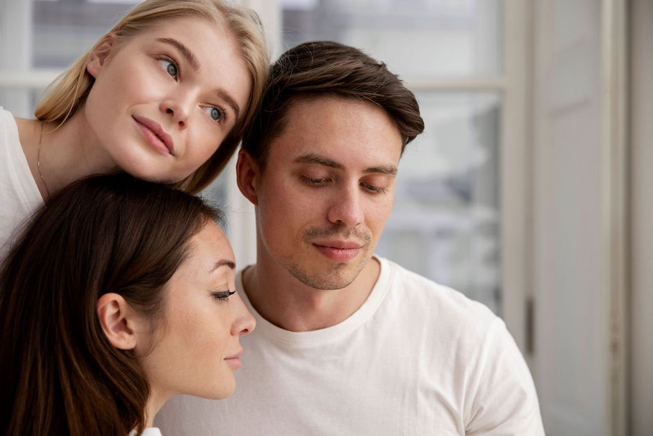 Three people gathered closely, smiling softly in a bright indoor setting.
