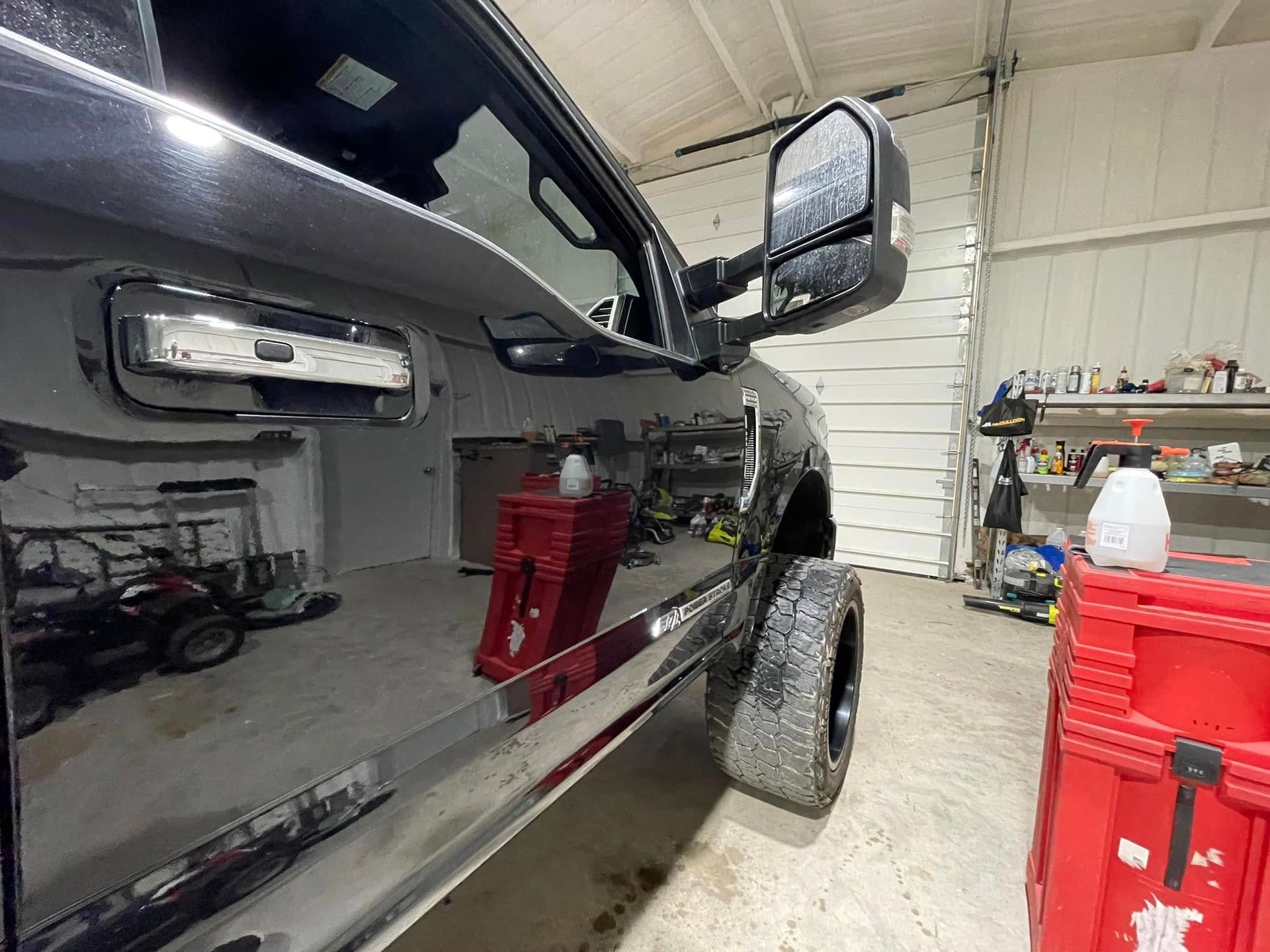 A black truck is parked in a garage next to a red box.