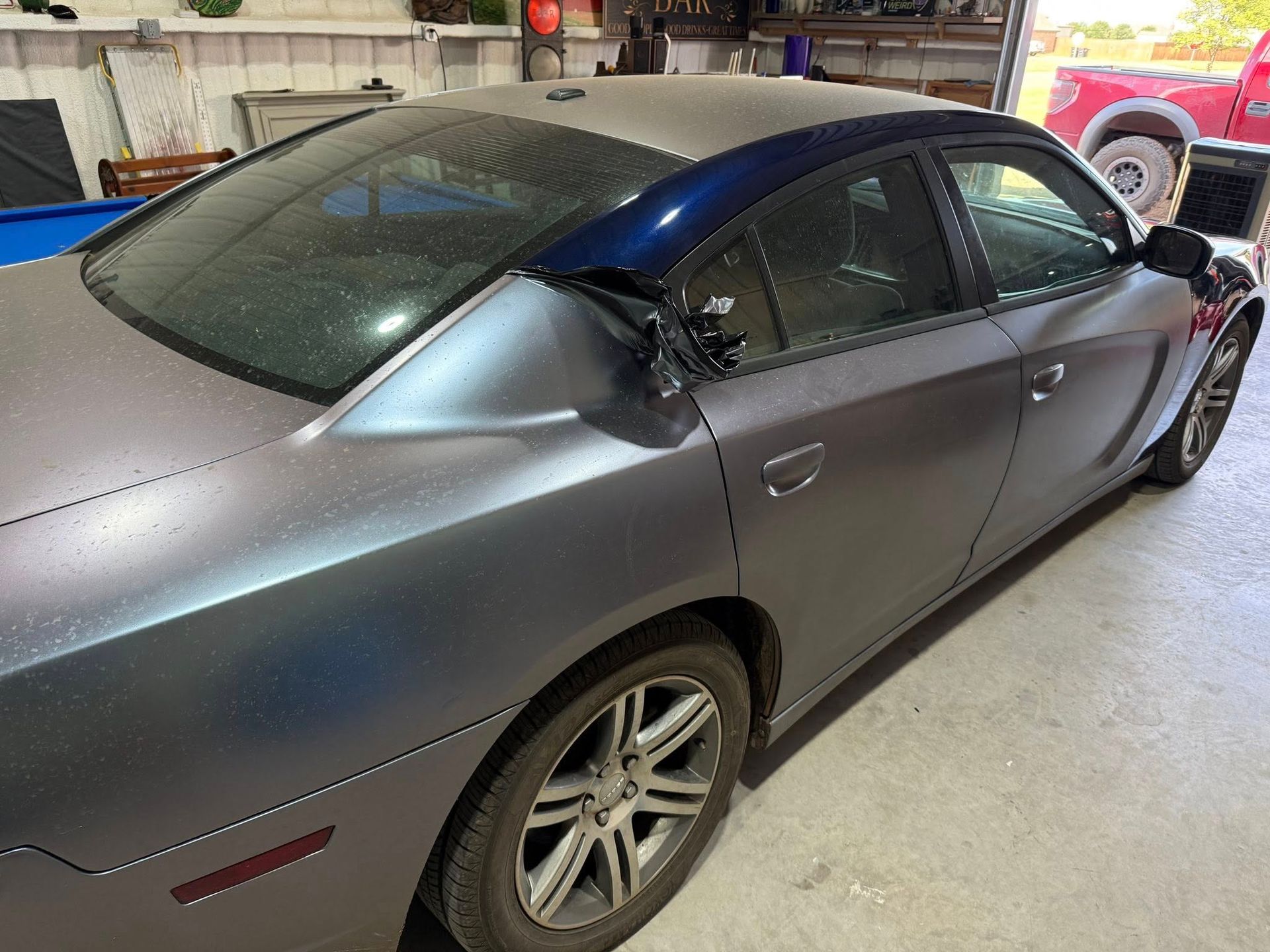 A gray and blue car is parked in a garage.