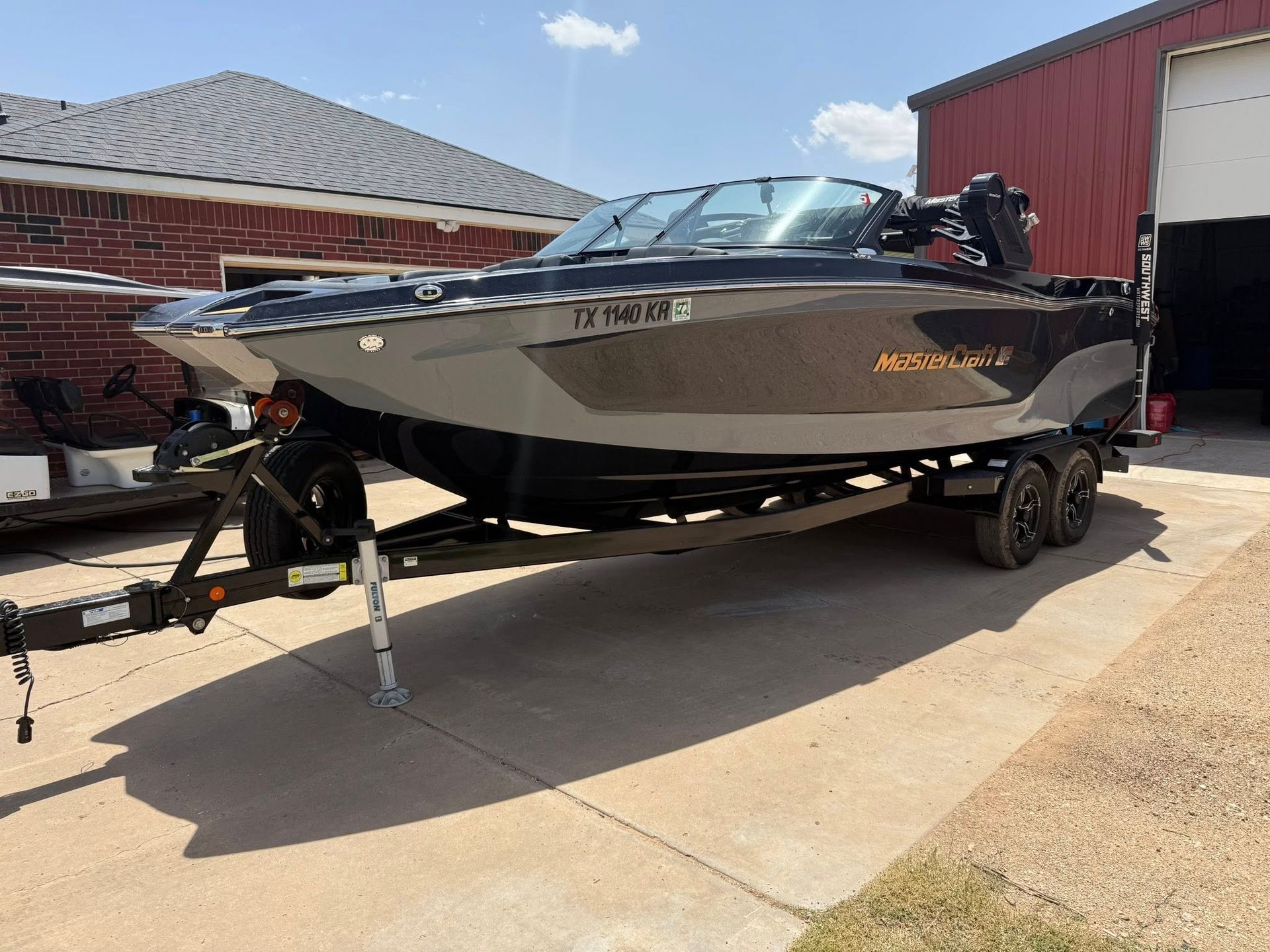 A boat is parked on a trailer in front of a garage.