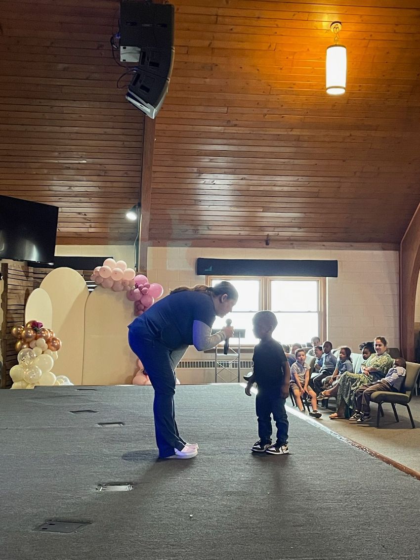 A man is standing on a stage talking to a little boy.