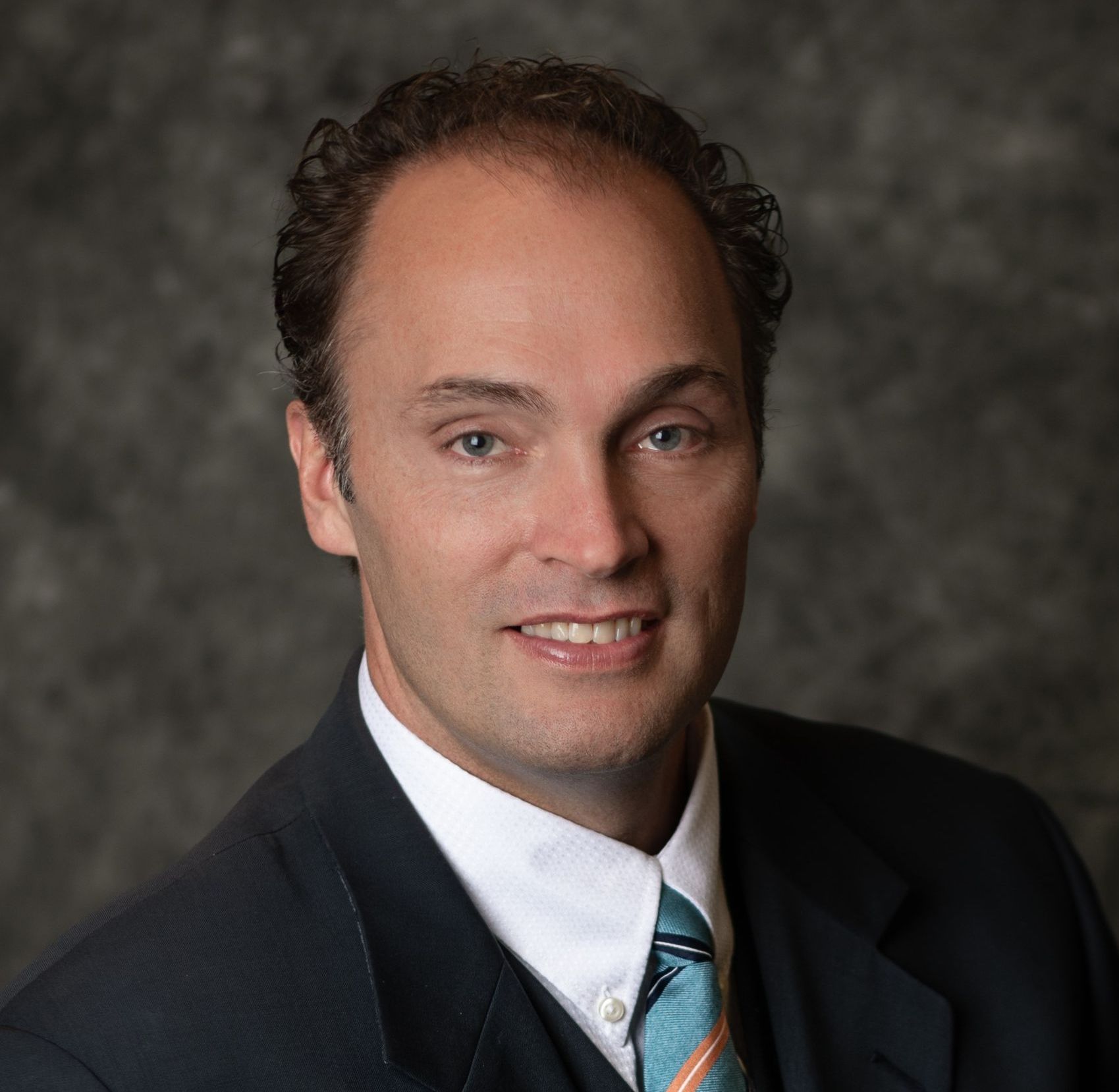 A man in a suit and tie is smiling for the camera