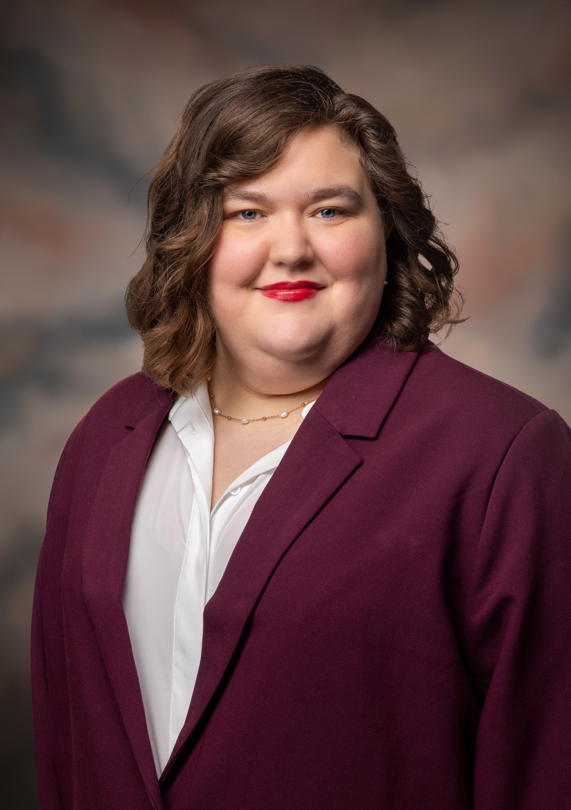 A woman in a purple jacket and white shirt is smiling for the camera.