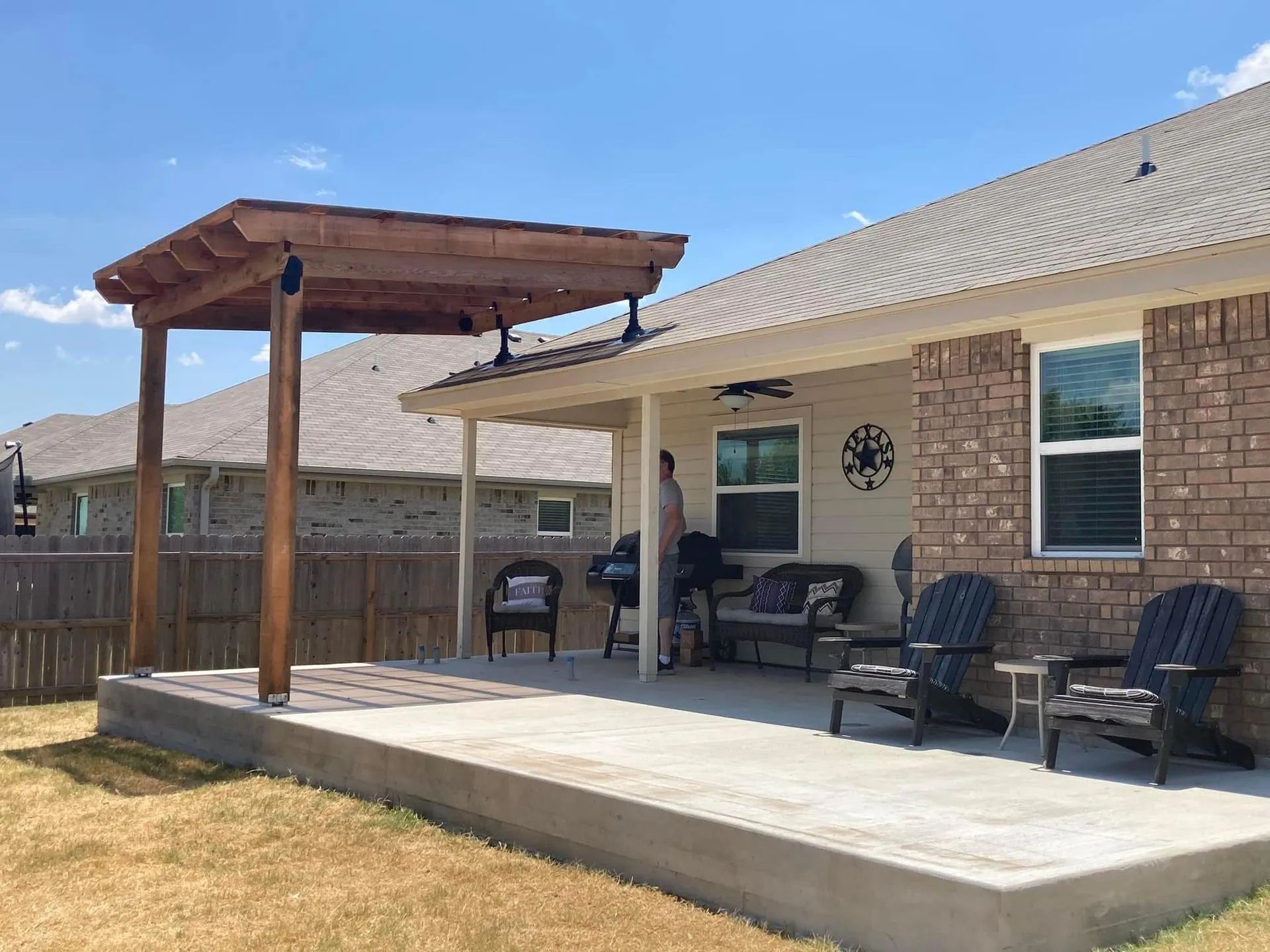 Back patio with concrete slab, pergola, and outdoor seating beside a brick house
