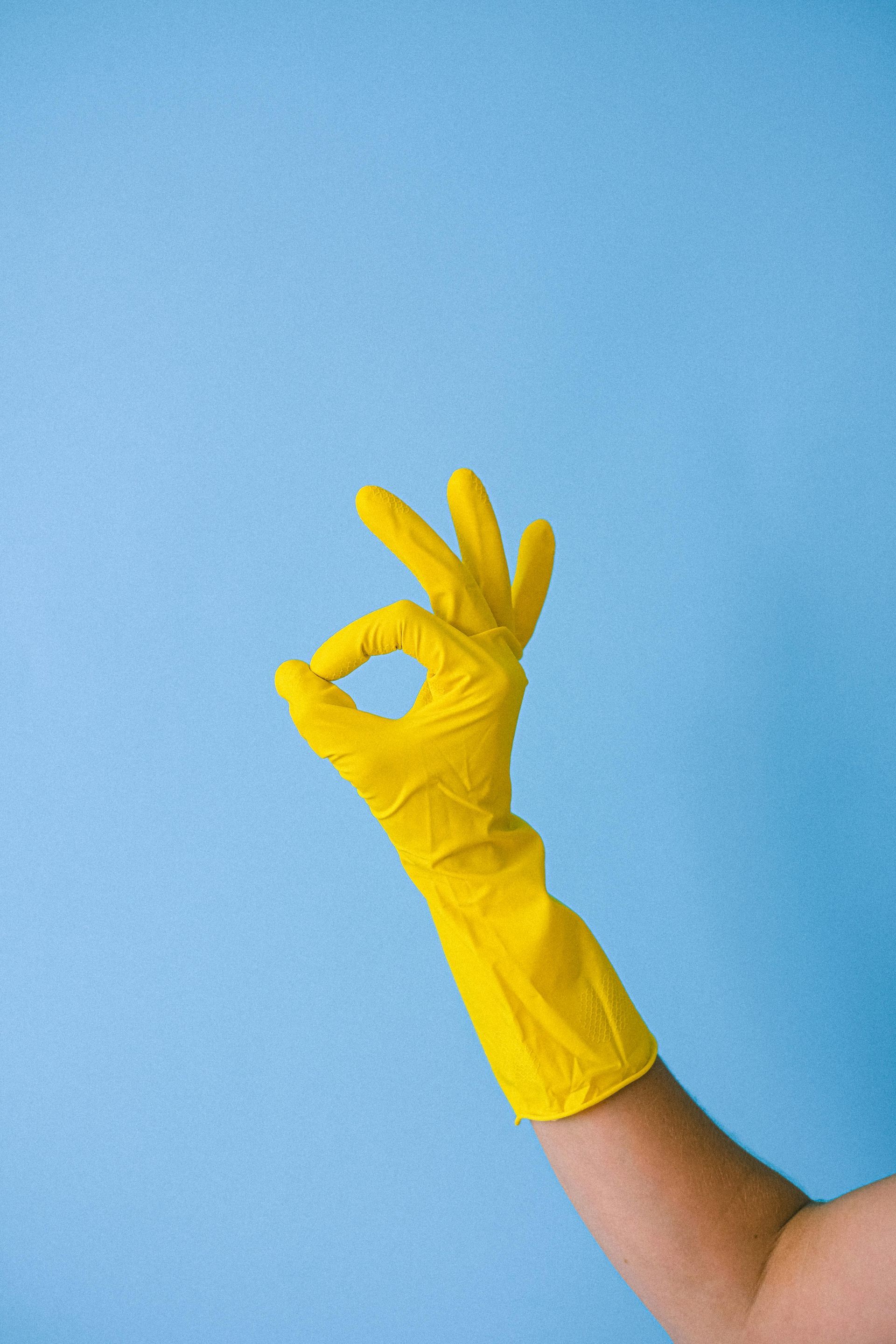 Arm wearing a yellow rubber glove making an 