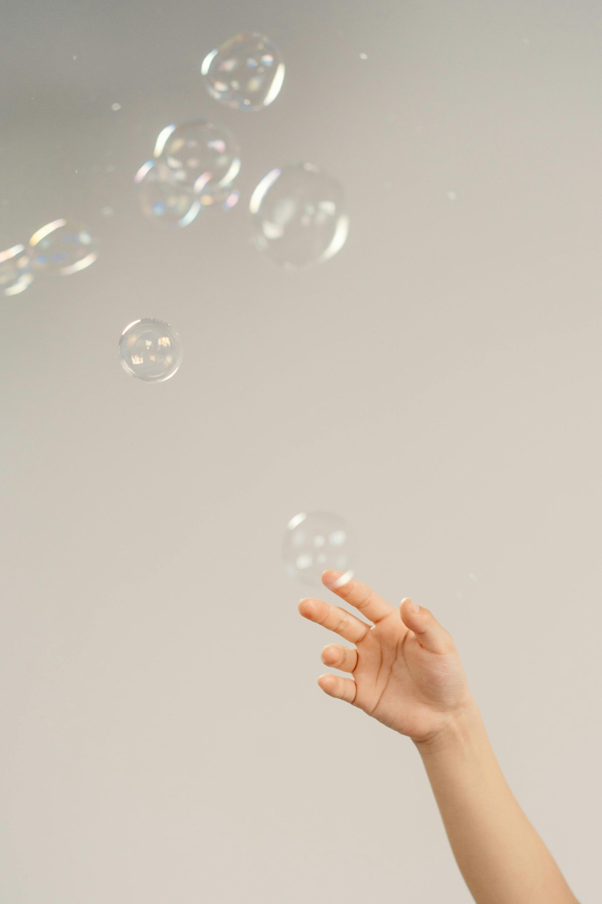 Hand reaching for floating soap bubbles.