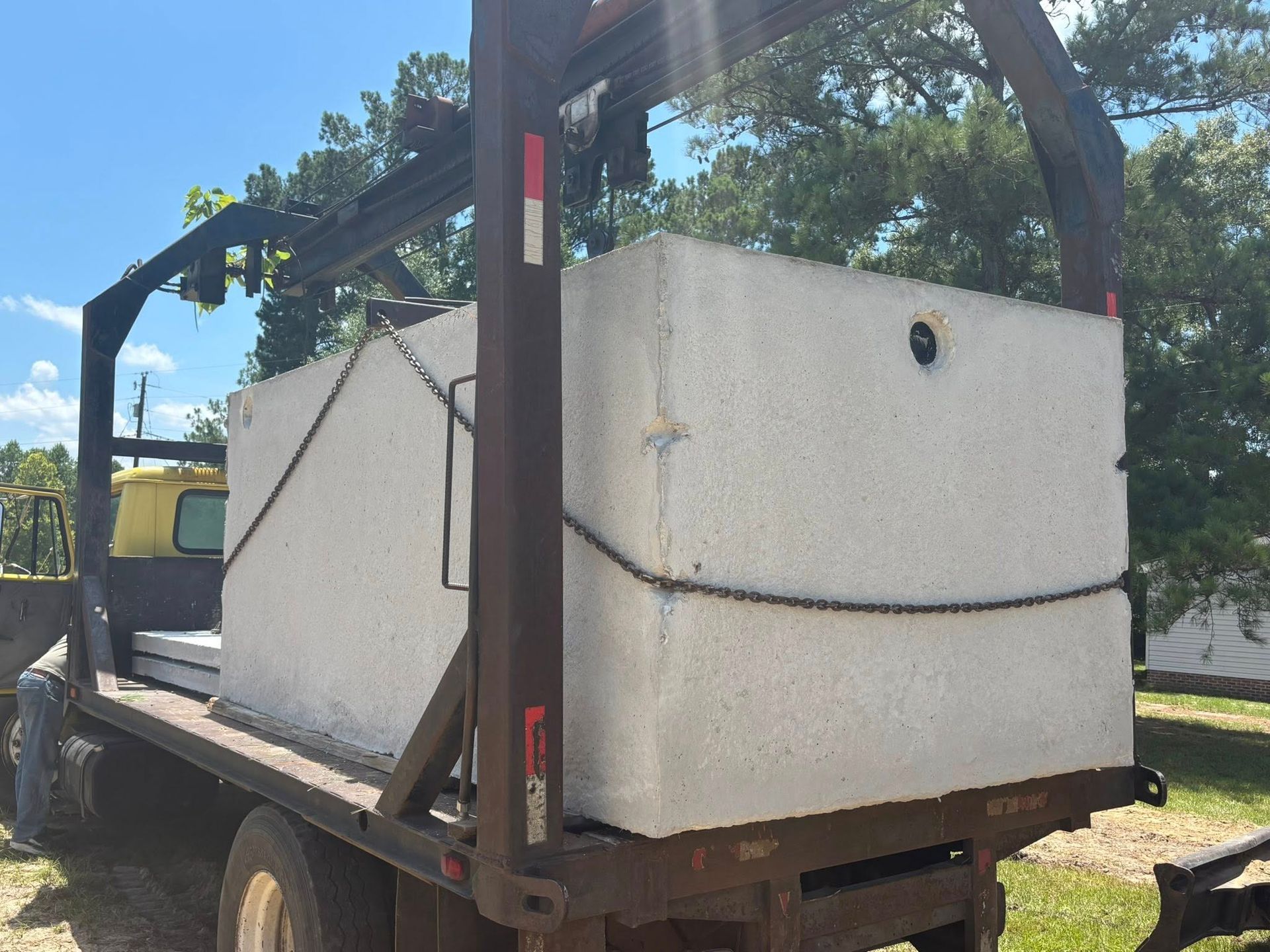 Concrete septic tank secured on a flatbed trailer, ready for transport.