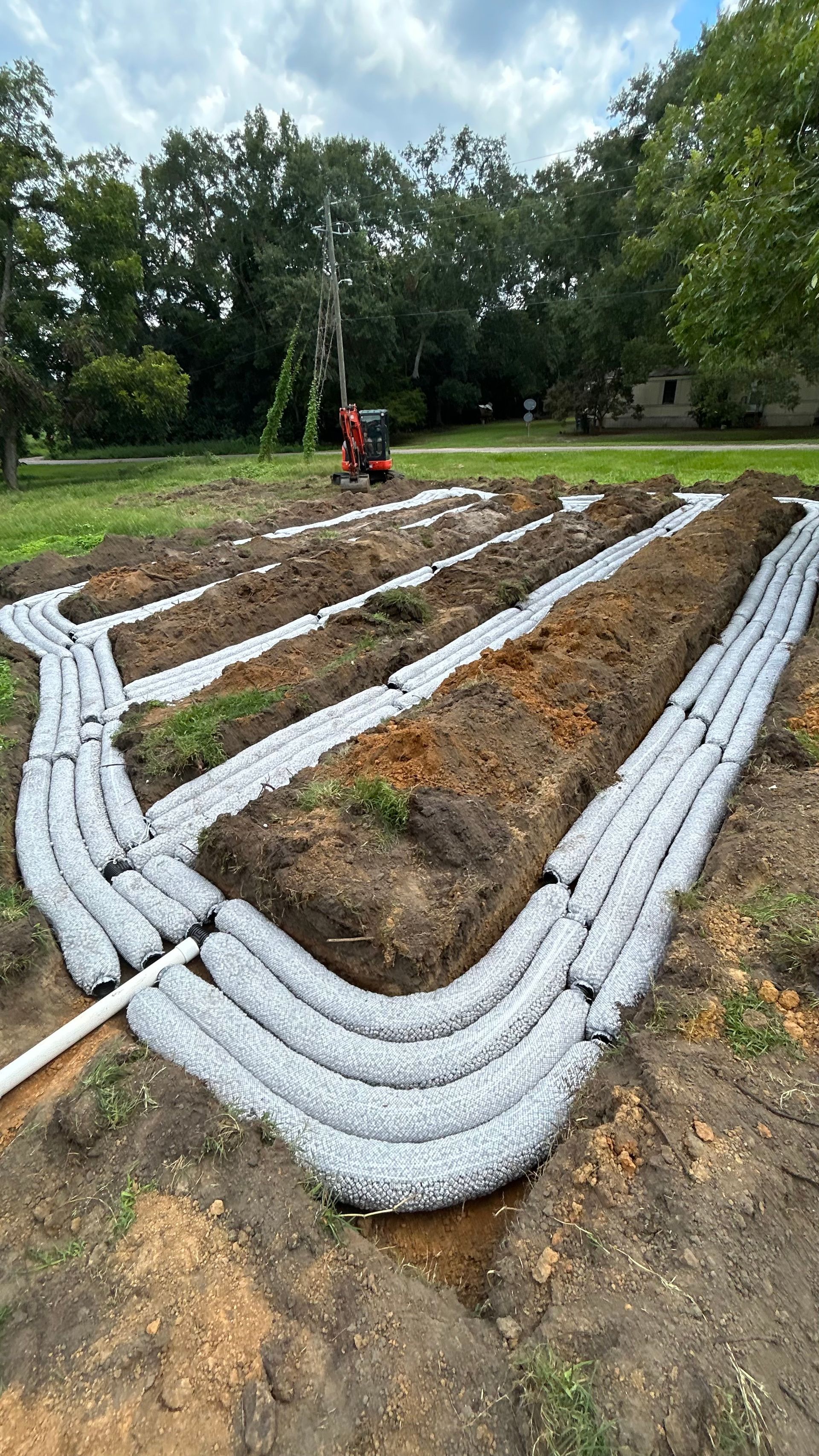 Raised garden beds outlined with white sandbags in a green park, with a person in red in the background