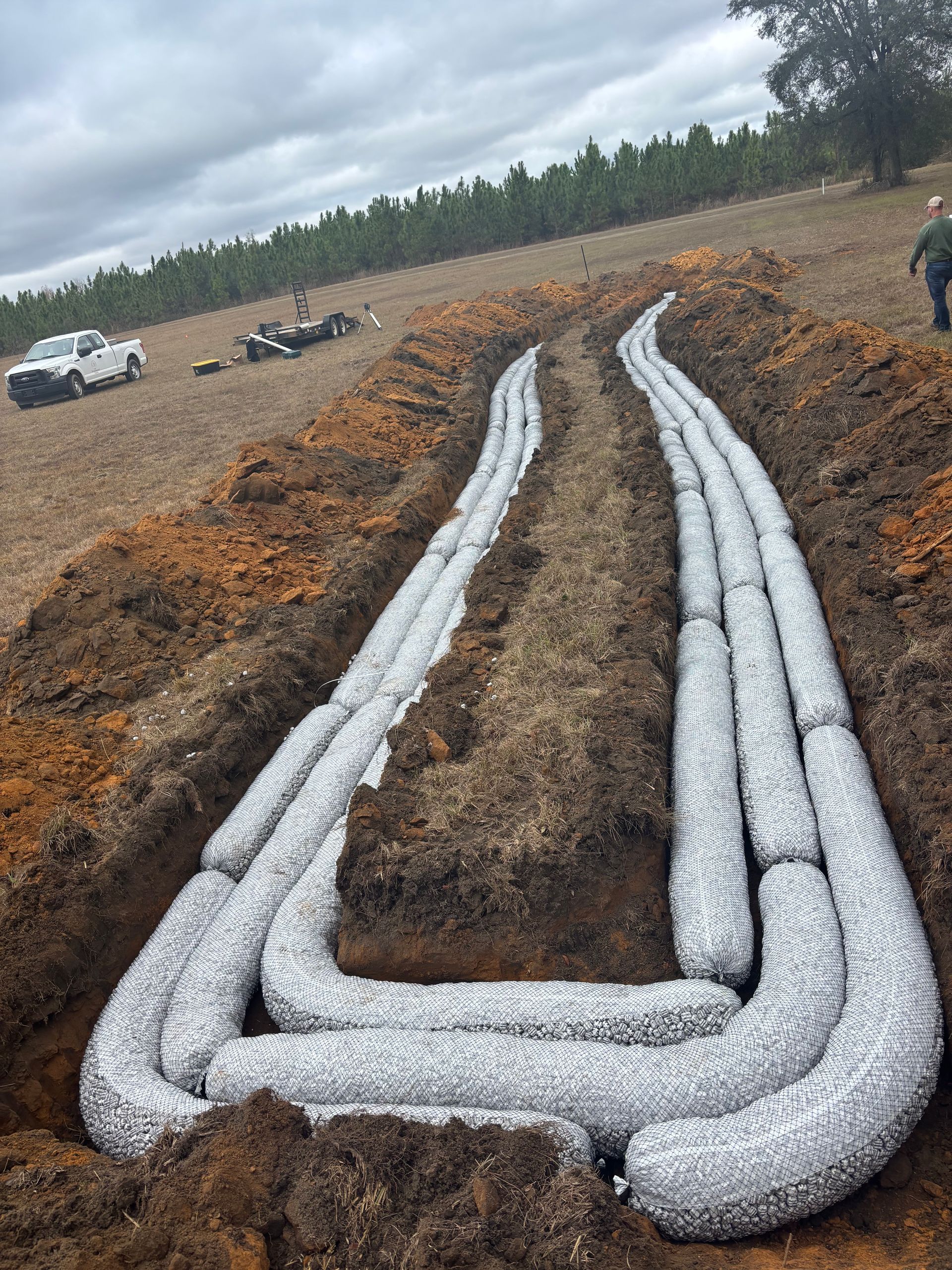 Trenches lined with woven fabric filled with gravel; a possible drainage system under construction.
