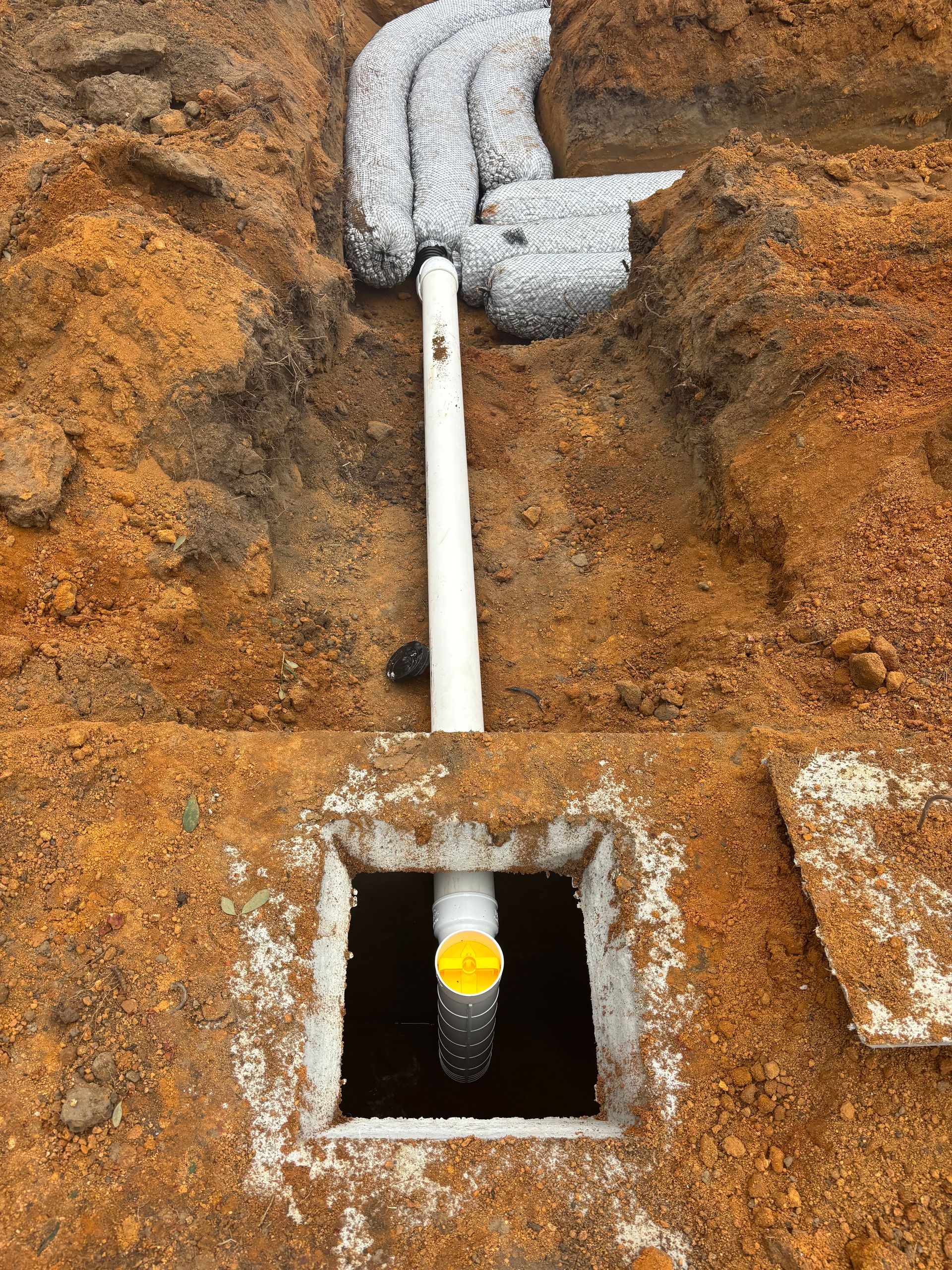White pipe entering a square hole in an orange-brown surface, with a small yellow object inside.