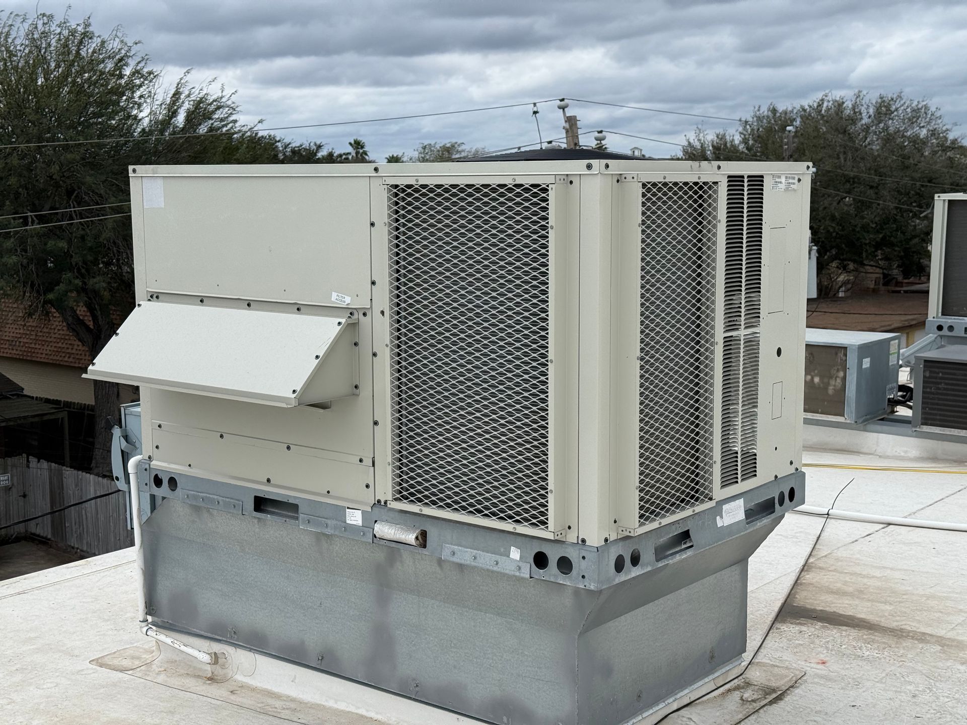 Outdoor Trane air conditioning unit beside a white house wall and basement window well