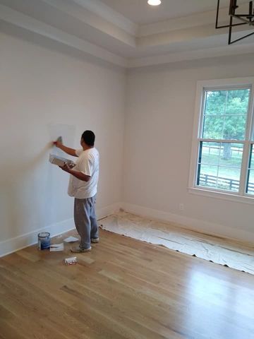 A man is painting a wall in a room.