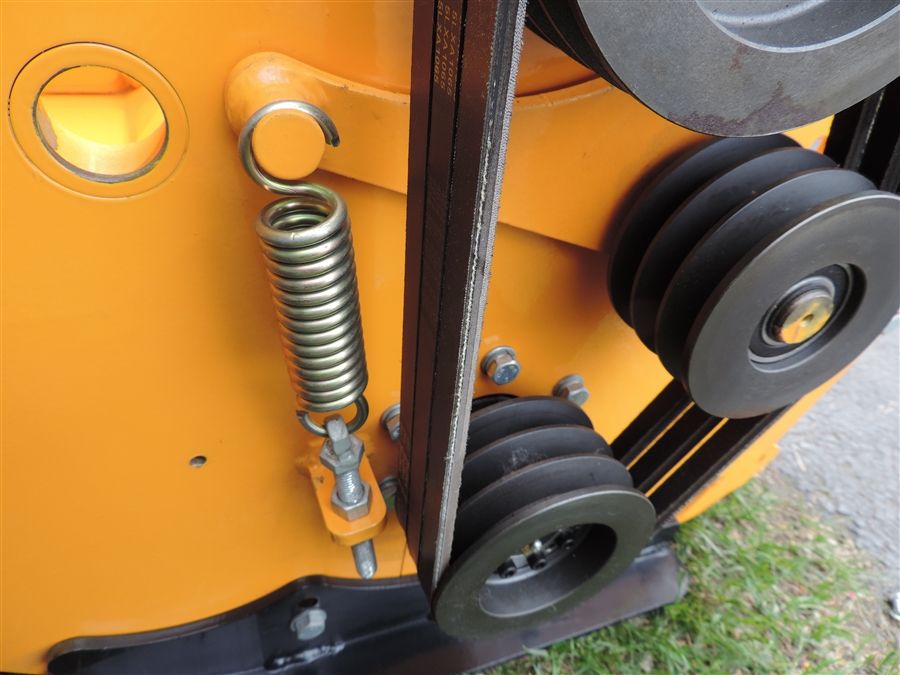 Close-up of a yellow machine part with a spring and black pulleys