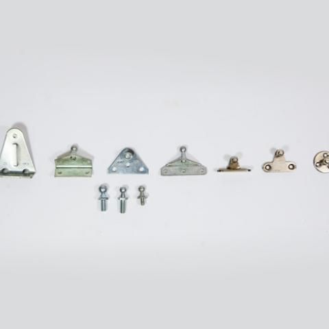 Assorted small metal brackets, hooks, and fasteners arranged in a row on a white background