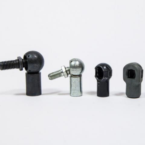 Four small metal rod end bearings in black, silver, and dark gray on a white background
