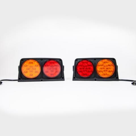 Two black dual-lens vehicle lights with orange and red circular lenses on a white background