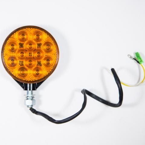 Amber round LED light with black cable and green connector on a white background