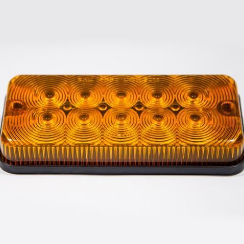 Amber rectangular vehicle marker light with black base and concentric circular lens pattern