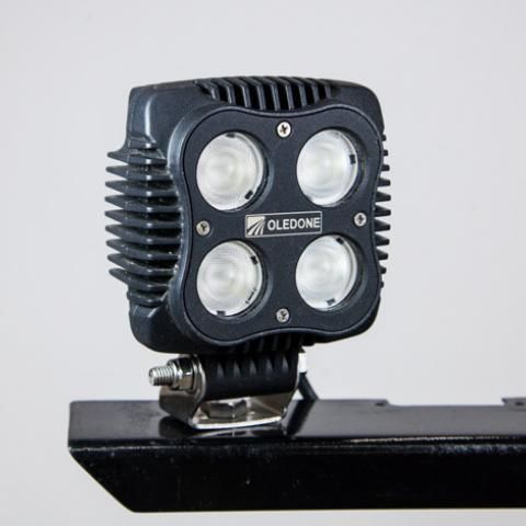 Black four-lens LED spotlight mounted on a metal bracket