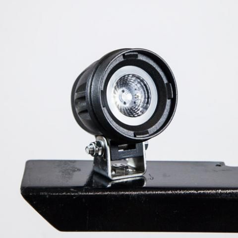 Small black circular device mounted on a black surface against a light background