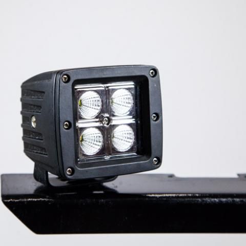 Black square LED light mounted on a black bracket with four bright bulbs