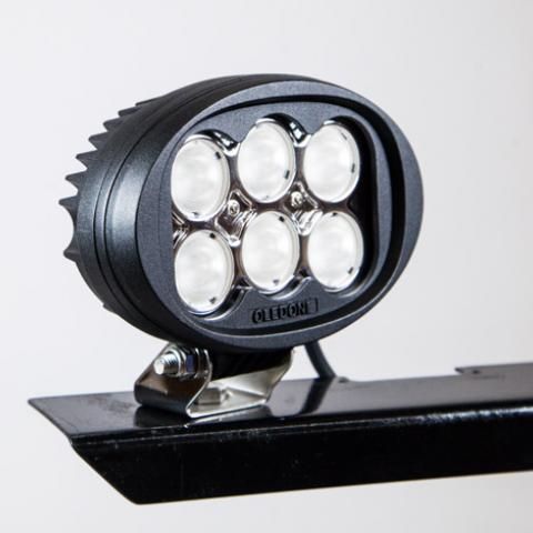 Black round LED light mounted on a metal bracket on a vehicle bar, shown against a light background