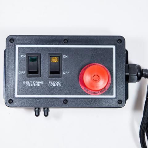 Control panel with black switches, amber indicator light, and large red emergency button on a white background