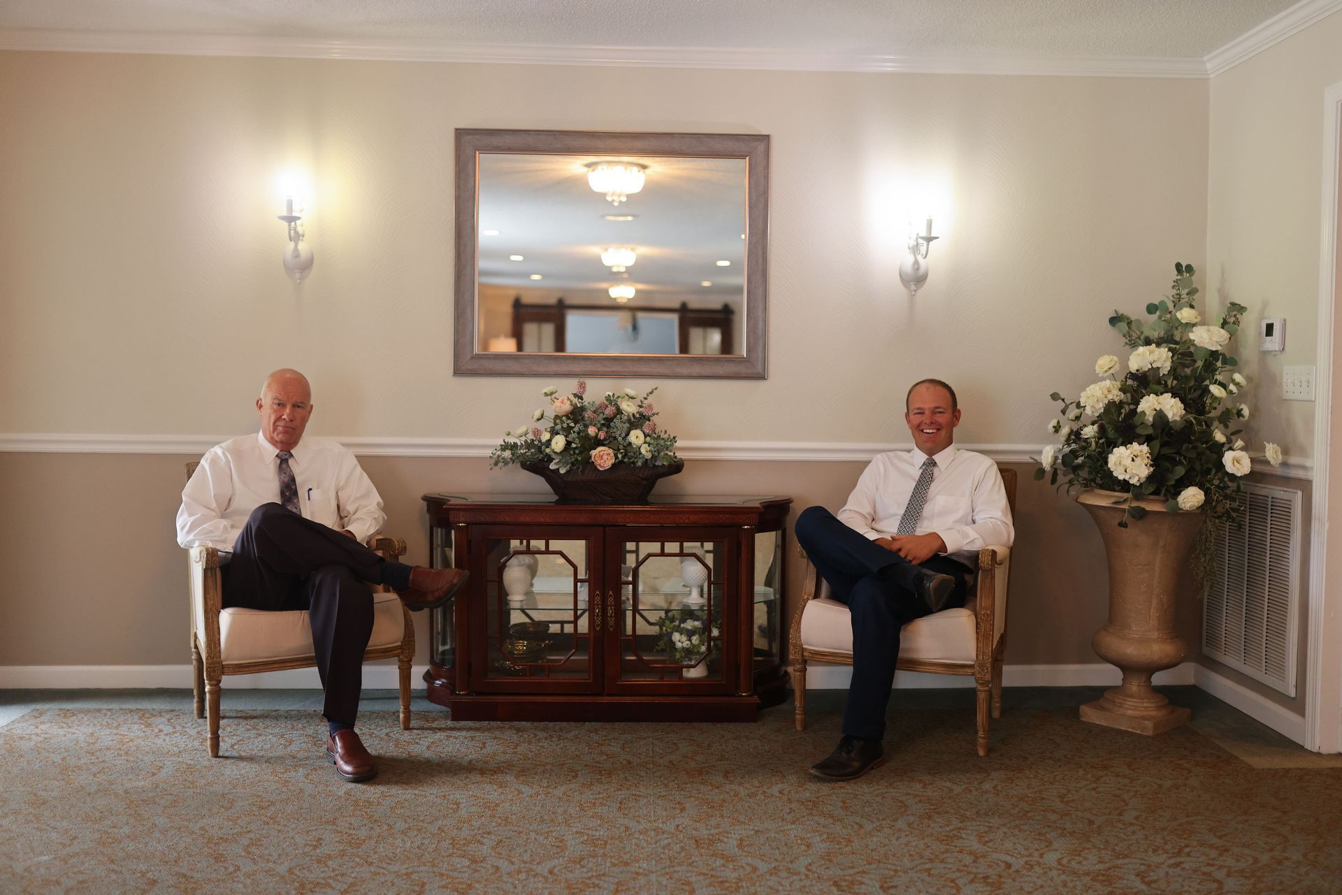 Two men are sitting in chairs in a living room
